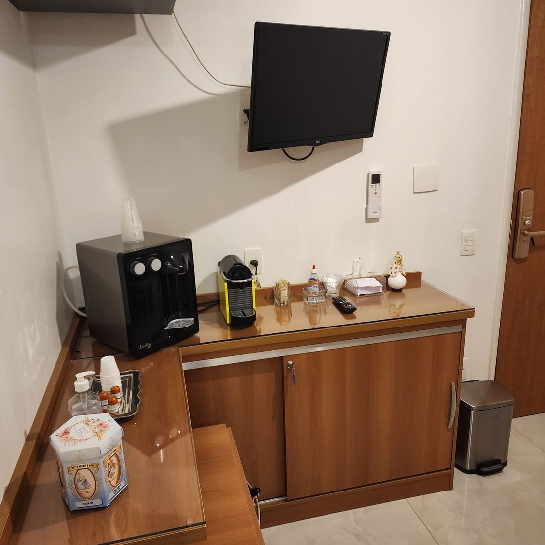 Bancada da copa com purificador de água, máquina de café em cápsulas, chás e televisão