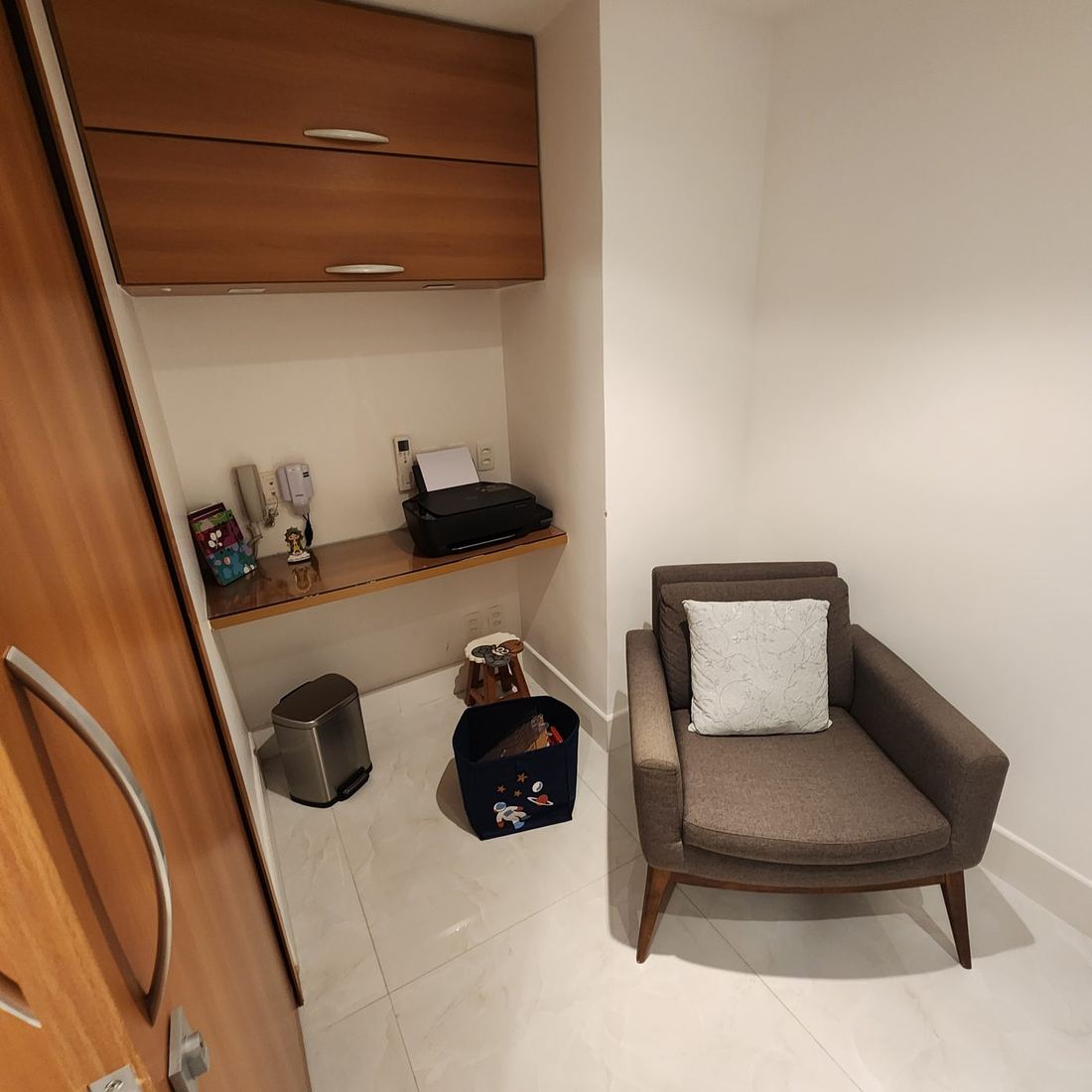 Outro ângulo da sala, com poltrona, nicho de trabalho e armário